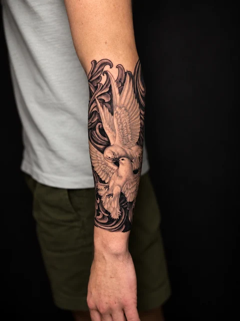 Black and gray doves and ornamental scrollwork on a forearm