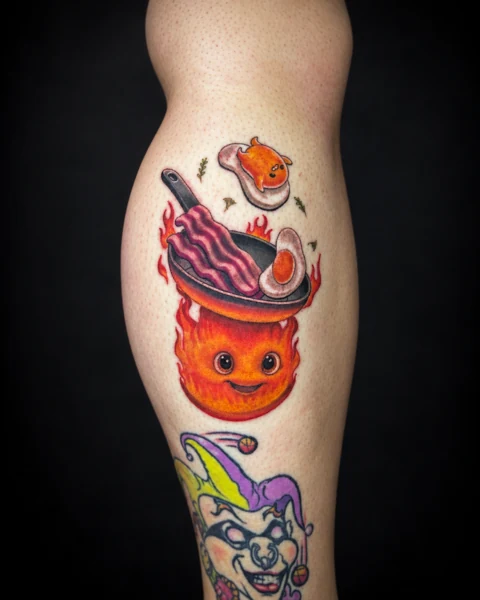 Colorful fire character with a frying pan, bacon and eggs tattoo