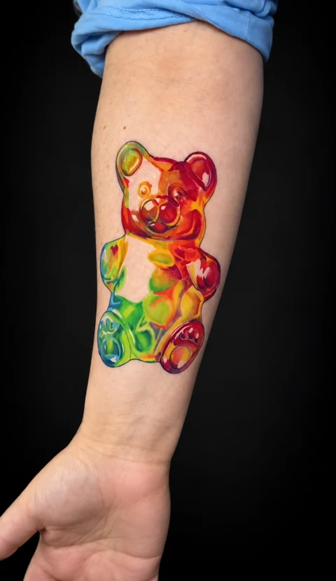 Multicolored gummy bear tattoo on an inner forearm